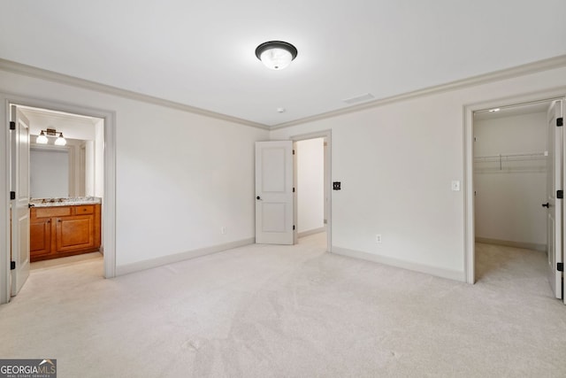 unfurnished bedroom featuring crown molding, light colored carpet, a spacious closet, baseboards, and a closet