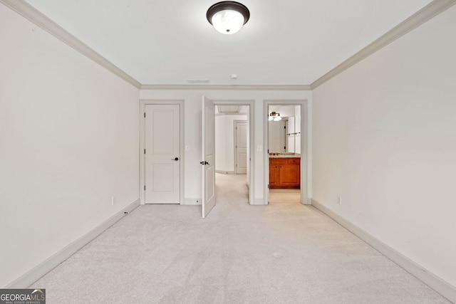 unfurnished bedroom with crown molding, light colored carpet, baseboards, and ensuite bath