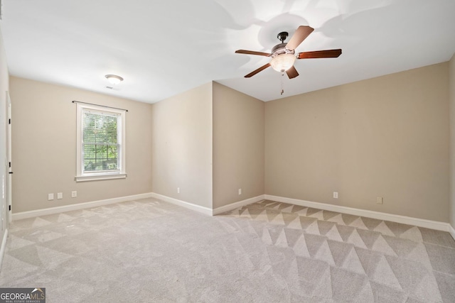 empty room with light carpet, a ceiling fan, and baseboards