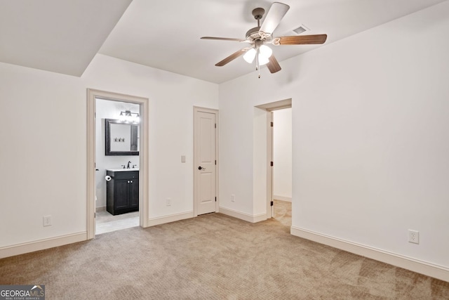 unfurnished bedroom with light carpet, ensuite bath, baseboards, and a sink