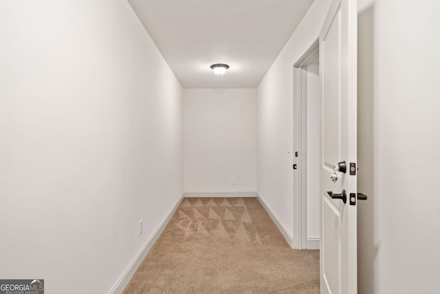 hallway featuring light carpet and baseboards