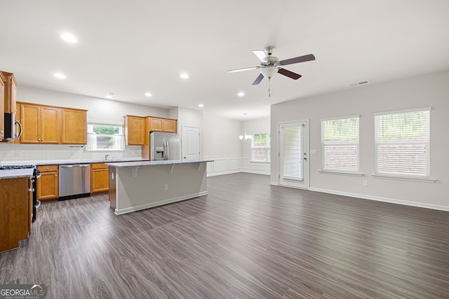 131 Prominence Ct, Canton, GA 30114 - kitchen featuring appliances with stainless steel finishes, a center island, a ceiling fan, dark wood-style floors, and a breakfast bar area