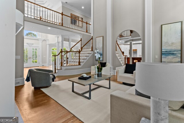3905 Merriweather Woods, Johns Creek, GA 30022 - living room featuring a towering ceiling, stairs, wood finished floors, arched walkways, and ornamental molding
