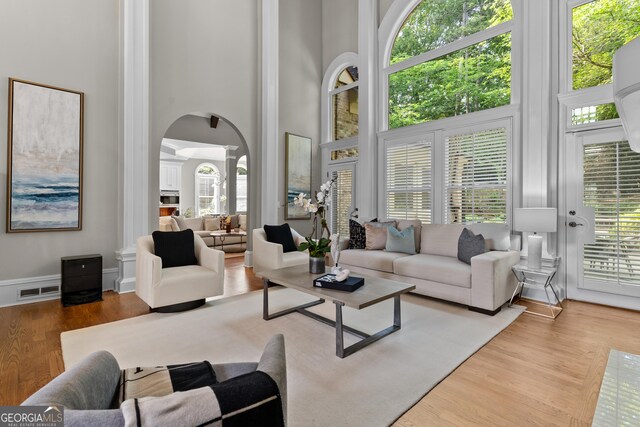 3905 Merriweather Woods, Johns Creek, GA 30022 - living room with arched walkways, a high ceiling, ornate columns, and wood finished floors