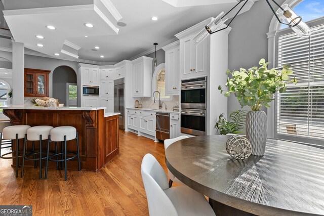3905 Merriweather Woods, Johns Creek, GA 30022 - kitchen featuring built in appliances, a breakfast bar area, light countertops, crown molding, and plenty of natural light