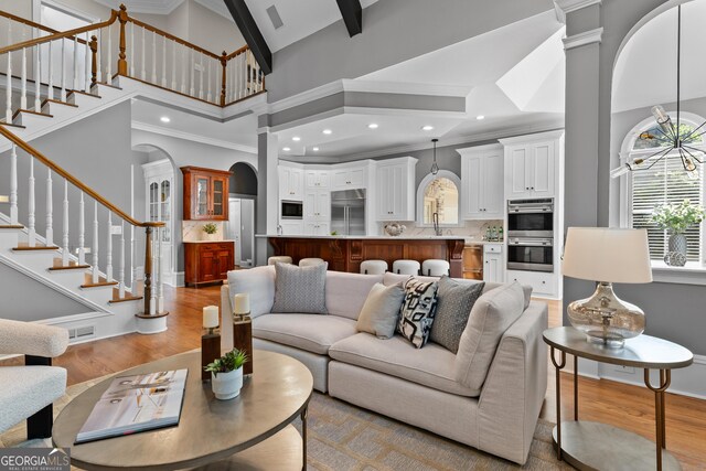 3905 Merriweather Woods, Johns Creek, GA 30022 - living area featuring high vaulted ceiling, light wood-type flooring, arched walkways, stairs, and crown molding