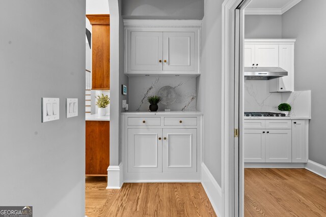 3905 Merriweather Woods, Johns Creek, GA 30022 - kitchen with under cabinet range hood, light wood-style flooring, decorative backsplash, white cabinetry, and light countertops