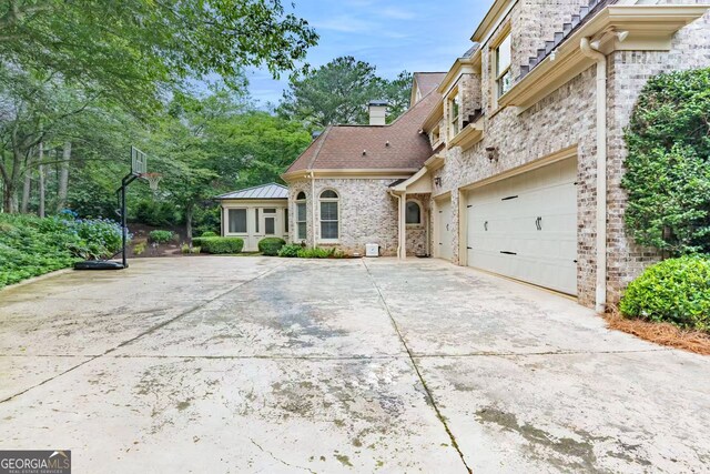 3905 Merriweather Woods, Johns Creek, GA 30022 - view of front of house with driveway, a garage, a chimney, stone siding, and brick siding
