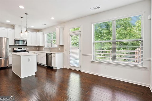 kitchen featuring stainless steel appliances, light countertops, white cabinets, baseboards, and backsplash