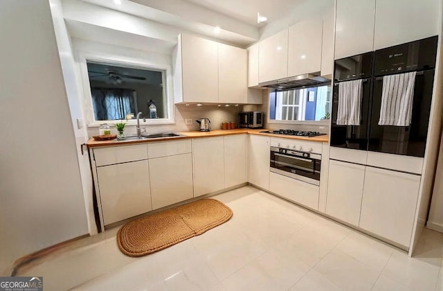 123 Hillview Dr, Thomaston, GA 30286 - kitchen with appliances with stainless steel finishes, a sink, under cabinet range hood, tasteful backsplash, and white cabinets