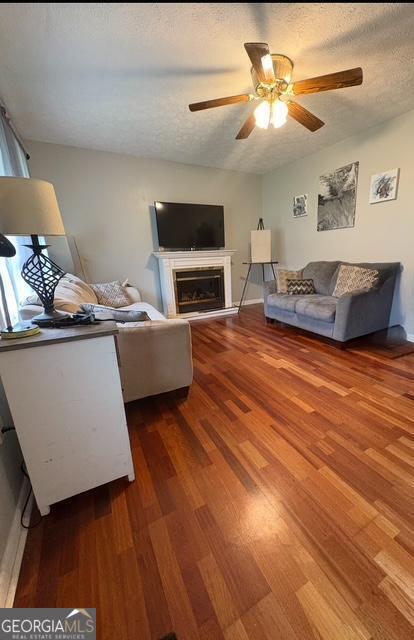 123 Hillview Dr, Thomaston, GA 30286 - living room with wood finished floors, ceiling fan, a textured ceiling, a fireplace, and baseboards