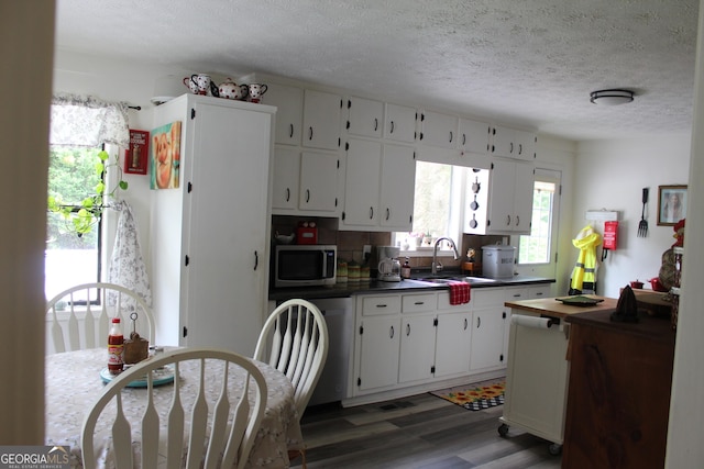 124 Wynn Rd, Mcdonough, GA 30252 - kitchen featuring stainless steel microwave, a sink, dark countertops, a textured ceiling, and wood finished floors