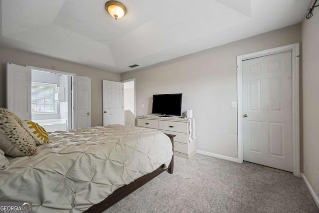 carpeted bedroom with baseboards and a raised ceiling