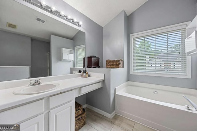 bathroom featuring lofted ceiling, a bath, tile patterned floors, plenty of natural light, and vanity