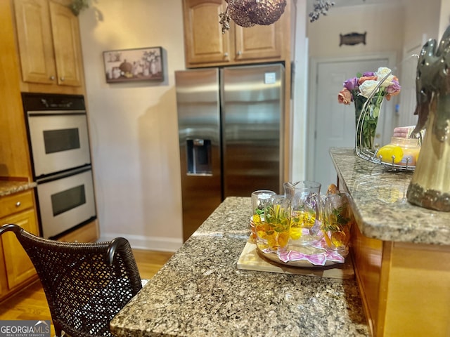 5430 Lemoyne Dr SW, South Fulton, GA 30331 - kitchen with white double oven, stainless steel fridge with ice dispenser, baseboards, and light stone countertops