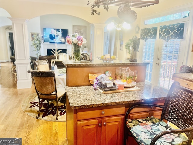5430 Lemoyne Dr SW, South Fulton, GA 30331 - kitchen with ornate columns, arched walkways, brown cabinetry, light stone countertops, and a center island