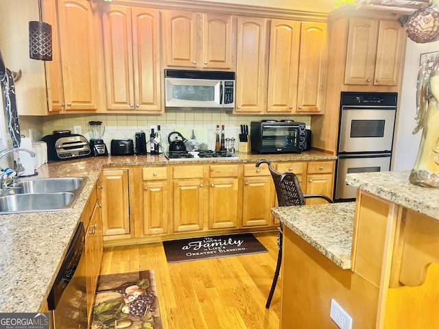5430 Lemoyne Dr SW, South Fulton, GA 30331 - kitchen with appliances with stainless steel finishes, a sink, light wood-style floors, backsplash, and a breakfast bar area
