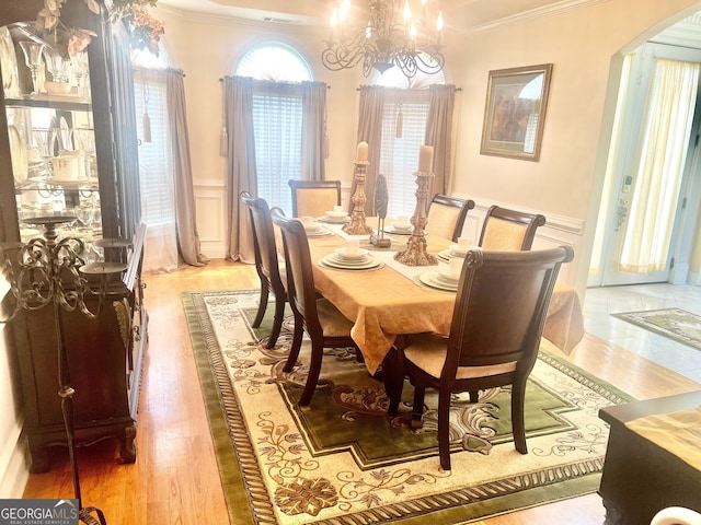 5430 Lemoyne Dr SW, South Fulton, GA 30331 - dining area featuring crown molding, arched walkways, a decorative wall, a chandelier, and a wainscoted wall