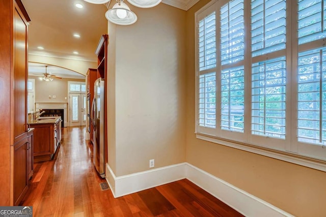 corridor featuring ornamental molding, wood finished floors, baseboards, and recessed lighting