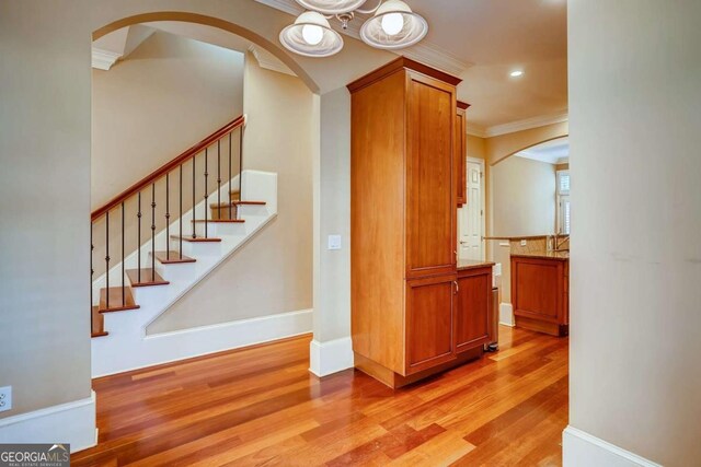 stairs featuring crown molding, wood finished floors, recessed lighting, arched walkways, and baseboards