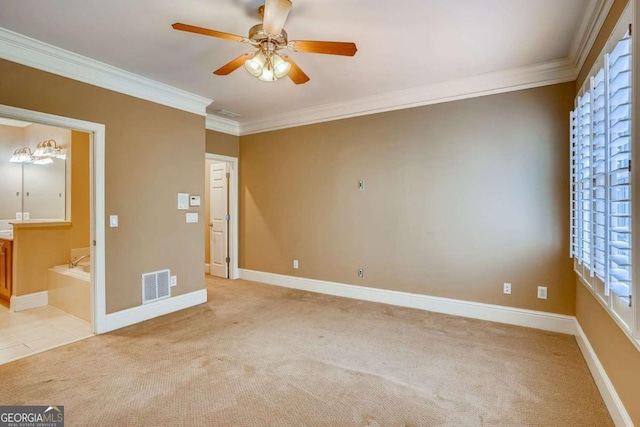 spare room featuring light colored carpet, ornamental molding, ceiling fan, and baseboards