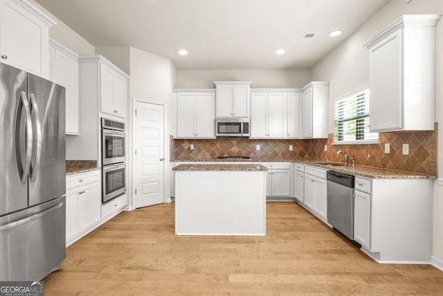 321 Shannon Ct, Mcdonough, GA 30252 - kitchen featuring appliances with stainless steel finishes, a kitchen island, light wood-type flooring, stone counters, and a sink