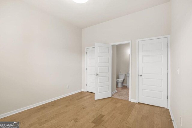 321 Shannon Ct, Mcdonough, GA 30252 - unfurnished bedroom with light wood finished floors, baseboards, and ensuite bathroom