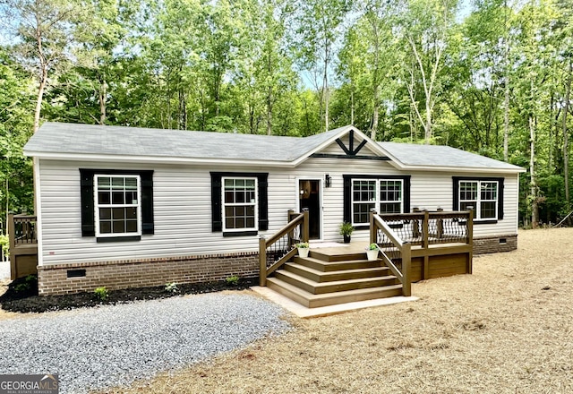 manufactured / mobile home featuring crawl space, a deck, and view of wooded area