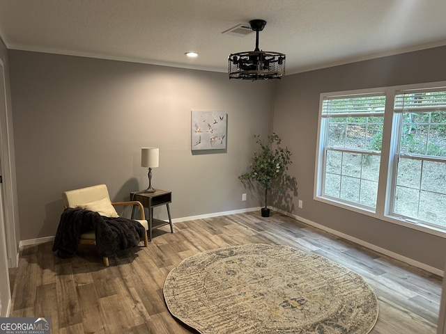 living area featuring a chandelier, wood finished floors, crown molding, baseboards, and a textured ceiling