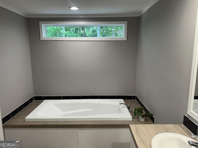 full bathroom with healthy amount of natural light, a bath, vanity, and ornamental molding