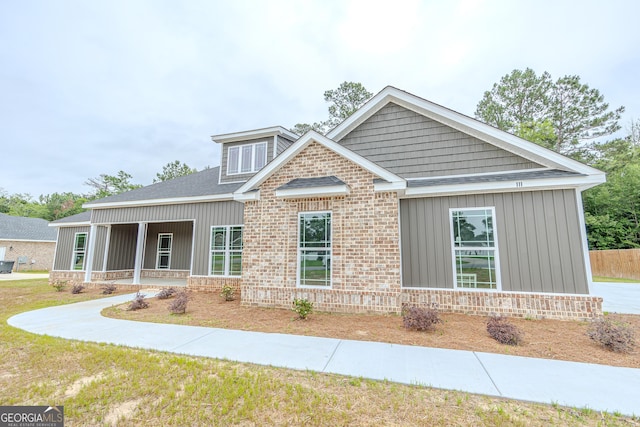 view of front of home with brick siding, board and batten siding, and a front yard
