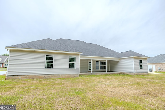 rear view of property with a patio area, a yard, and a shingled roof