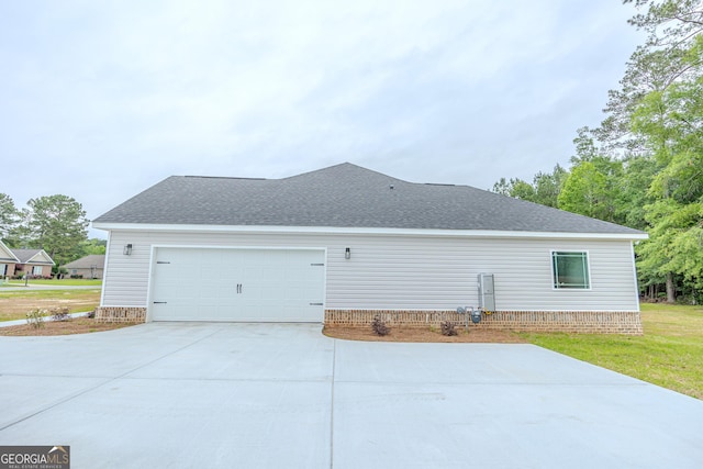 view of side of home featuring roof with shingles, concrete driveway, and an attached garage