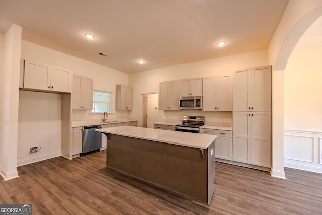 kitchen with stainless steel appliances, a sink, light countertops, arched walkways, and recessed lighting
