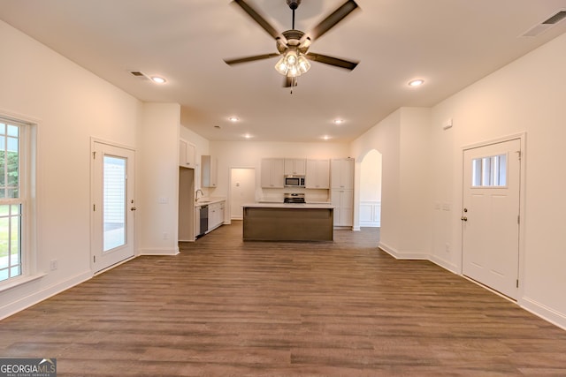 kitchen with stainless steel appliances, arched walkways, a ceiling fan, open floor plan, and dark wood-style flooring