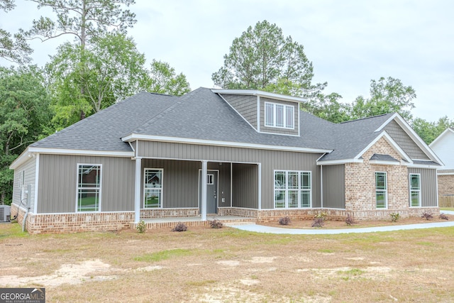 craftsman inspired home with a shingled roof, a porch, and central AC unit
