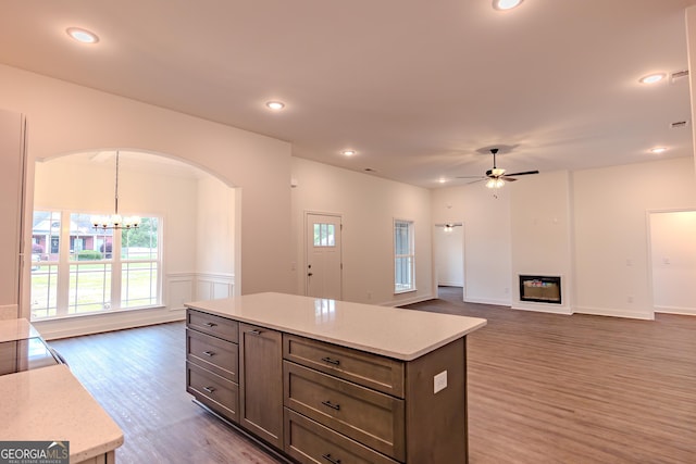 kitchen with arched walkways, a chandelier, healthy amount of natural light, wood finished floors, and recessed lighting
