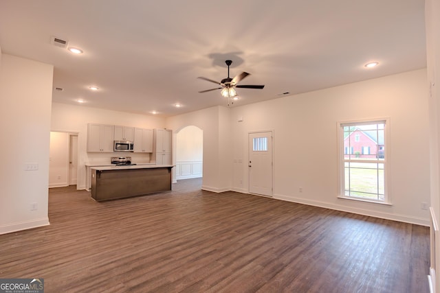 kitchen with appliances with stainless steel finishes, open floor plan, arched walkways, ceiling fan, and dark wood-type flooring