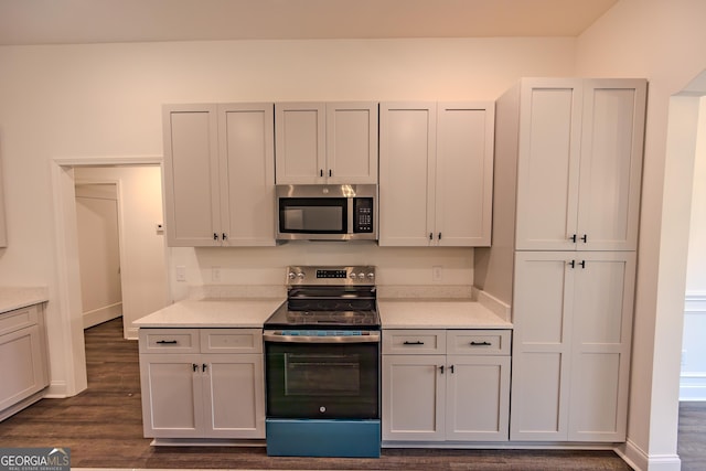kitchen featuring stainless steel appliances, dark wood finished floors, and light countertops