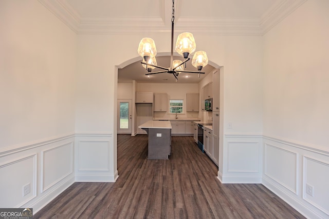kitchen featuring a chandelier, light countertops, a decorative wall, wainscoting, and crown molding