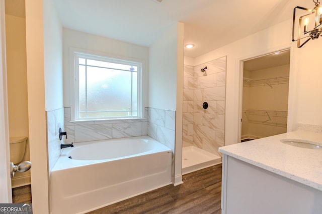 full bath featuring tiled shower, wood finished floors, a garden tub, a spacious closet, and vanity