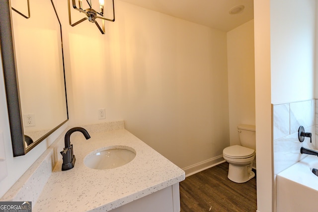full bathroom with toilet, wood finished floors, a bathtub, vanity, and baseboards