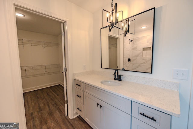 full bathroom featuring a chandelier, wood finished floors, a walk in closet, and a tile shower