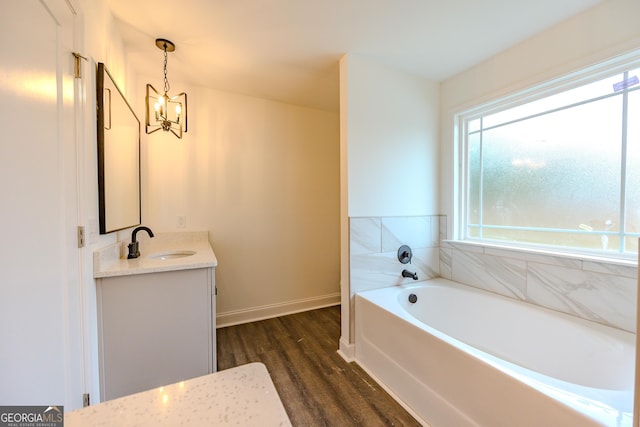 bathroom with healthy amount of natural light, wood finished floors, vanity, and a bath