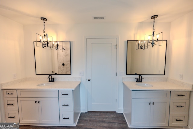 bathroom with a chandelier, wood finished floors, and two vanities