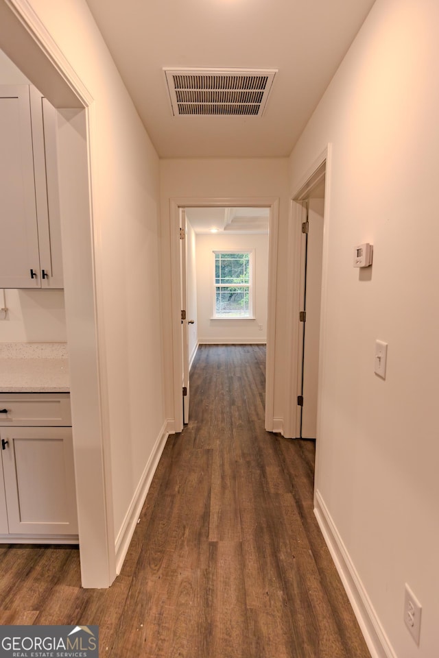 hall featuring dark wood-type flooring and baseboards