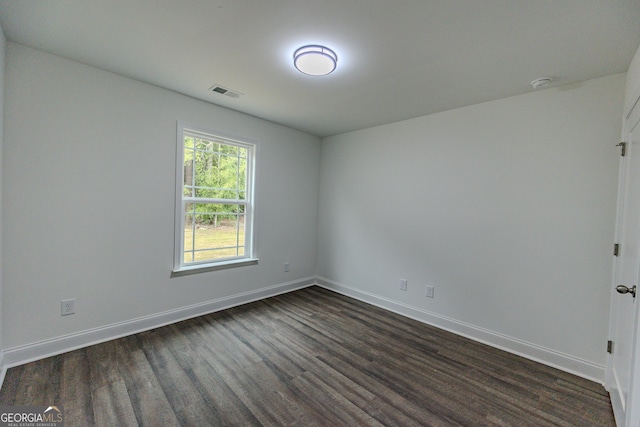 empty room featuring dark wood-style flooring, baseboards, and a smoke detector