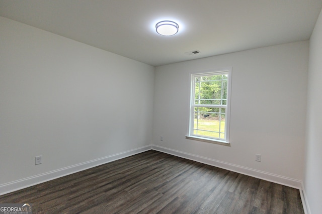 empty room with dark wood finished floors and baseboards