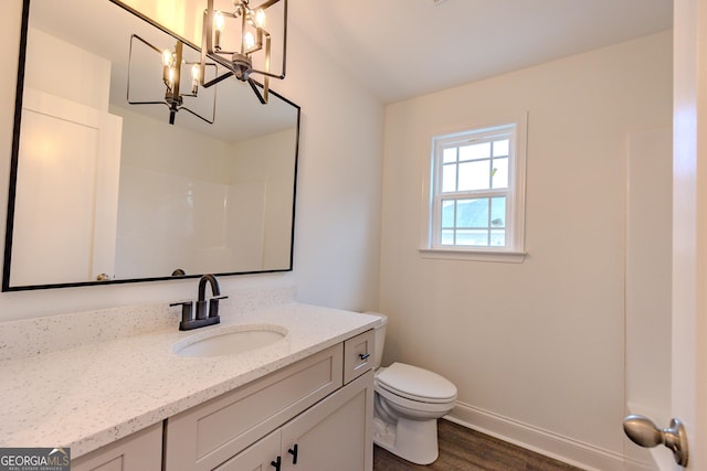 bathroom featuring toilet, vanity, a chandelier, baseboards, and wood finished floors