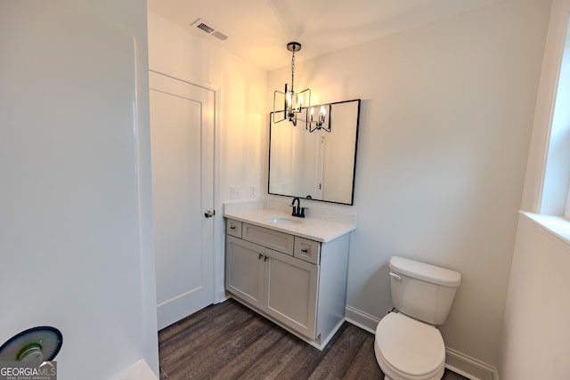 bathroom featuring wood finished floors, a chandelier, toilet, vanity, and baseboards